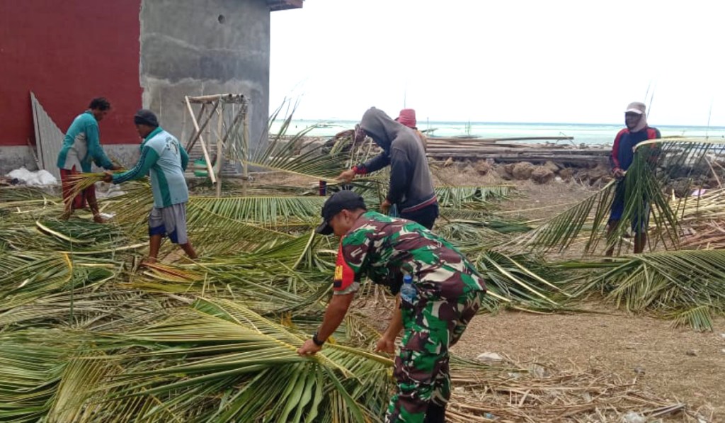 Peduli Sesama, TNI Bantu Warga Bersihkan Pohon Kelapa Yang Tumbang