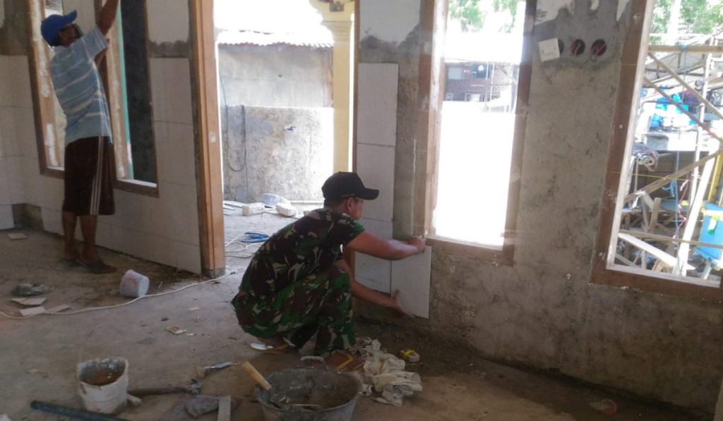 Bangun Sarana Ibadah, Babinsa Prenduan Bantu Warga Pasang Keramik dinding Mushola